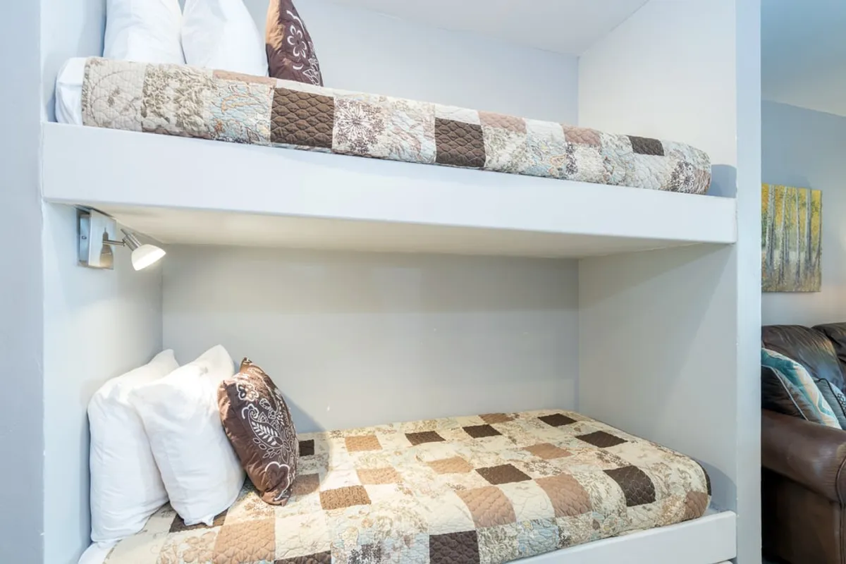 Close-up of bunk beds adorned with quilts and decorative pillows, exuding comfort and warmth. The inviting arrangement suggests a perfect spot for bedtime stories or early morning laughter among siblings.