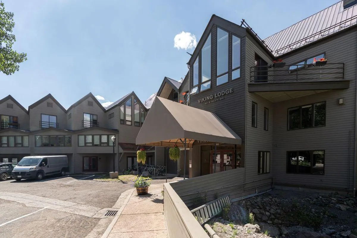 The entrance of Viking Lodge, marked by its welcoming sign and awning, with bicycles parked nearby and large windows offering a glimpse inside. The area feels lively and accessible, suggesting easy access to amenities and local adventures.