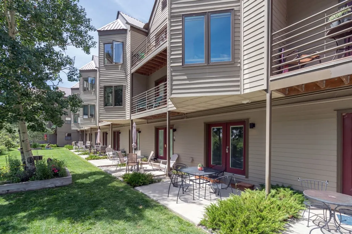 This image features balconies and an outdoor seating area set among landscaped gardens, with sunlight filtering through the trees. The setting is tranquil, perfect for enjoying a morning coffee or quiet evening outdoors, echoing the section's opening scene.